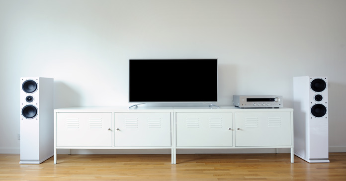 A modern, minimalist home theater set up with white tower speakers and a large white entertainment console.